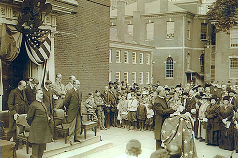 A man speaking to a large group of people, in late 19th century