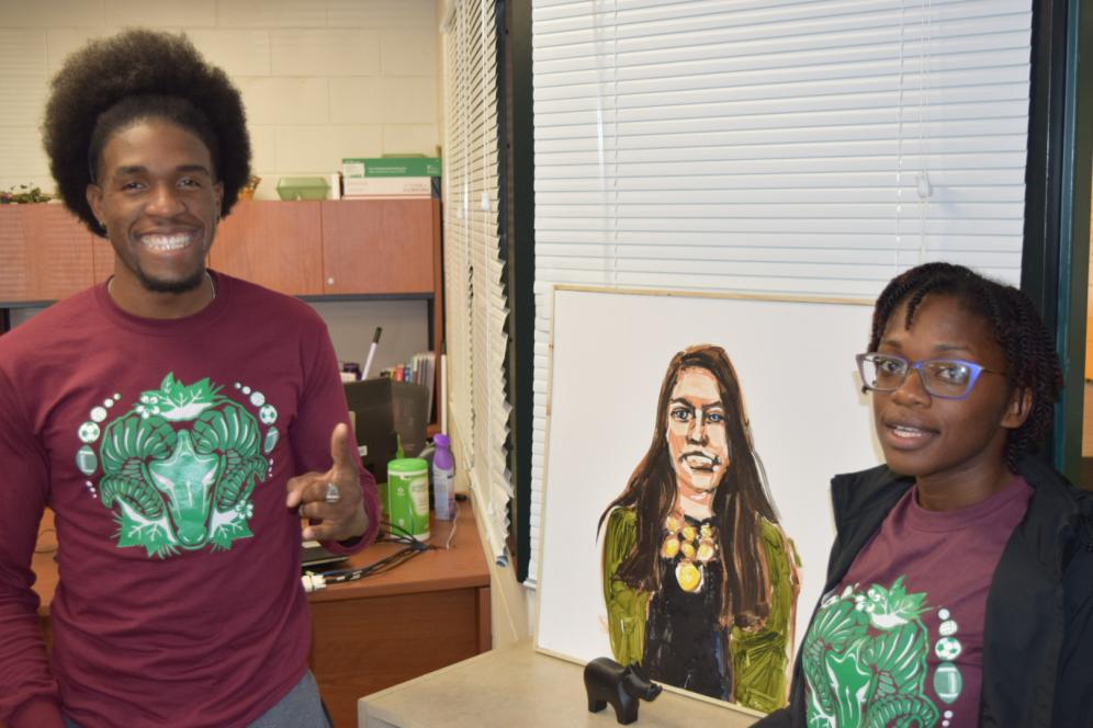 student and staff member posing next to art in the multicultural lounge.