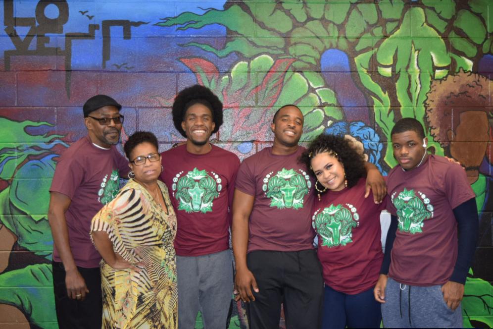 artist with family and friends posing in front of his mural in the multicultural lounge.