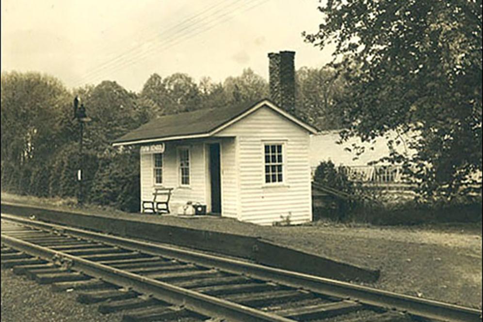 Old white wood shack that is a train station.