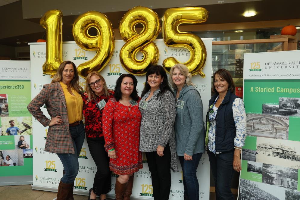 Alumna gather under 1985 balloons in the Life Sciences Building