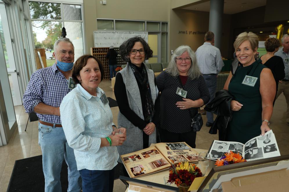Alumni are paging through a photo album in the Life Sciences Lobby.