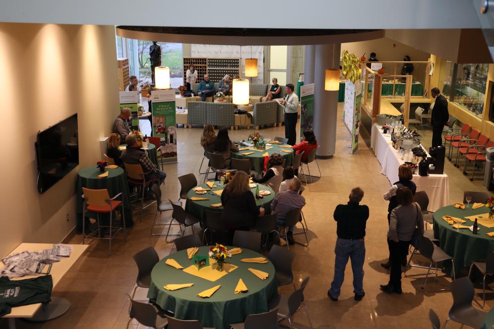 Alumni are gathered around tables that are set up with flowers and silverware.