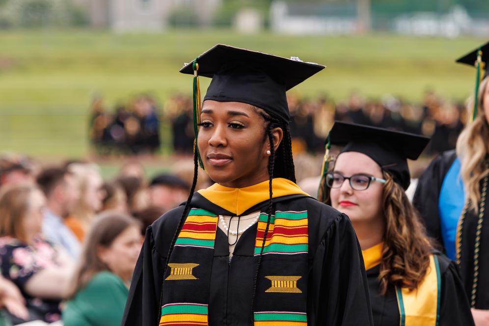 Graduate walking with cap and gown on.
