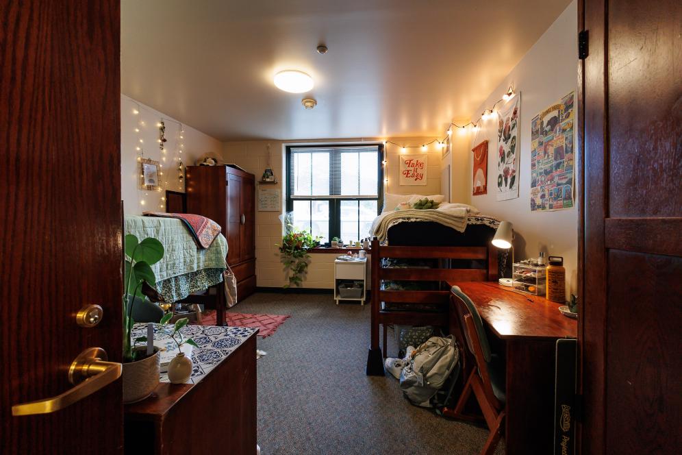A long shot of a typical dorm room set up with two beds and decorated by the students. 