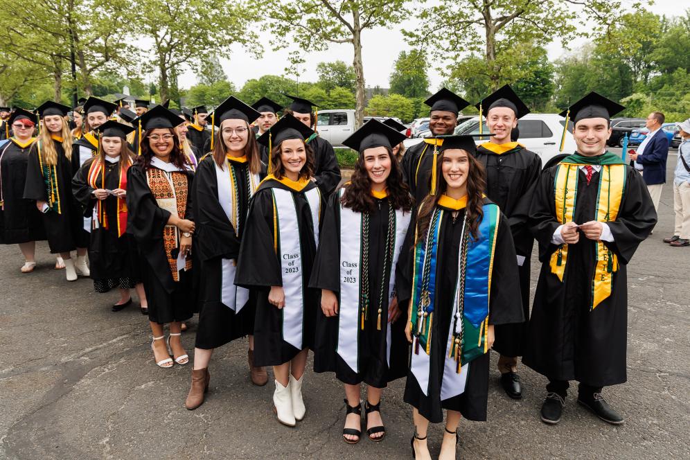 Student wearing regalia in a group photo smiling at commencement. 