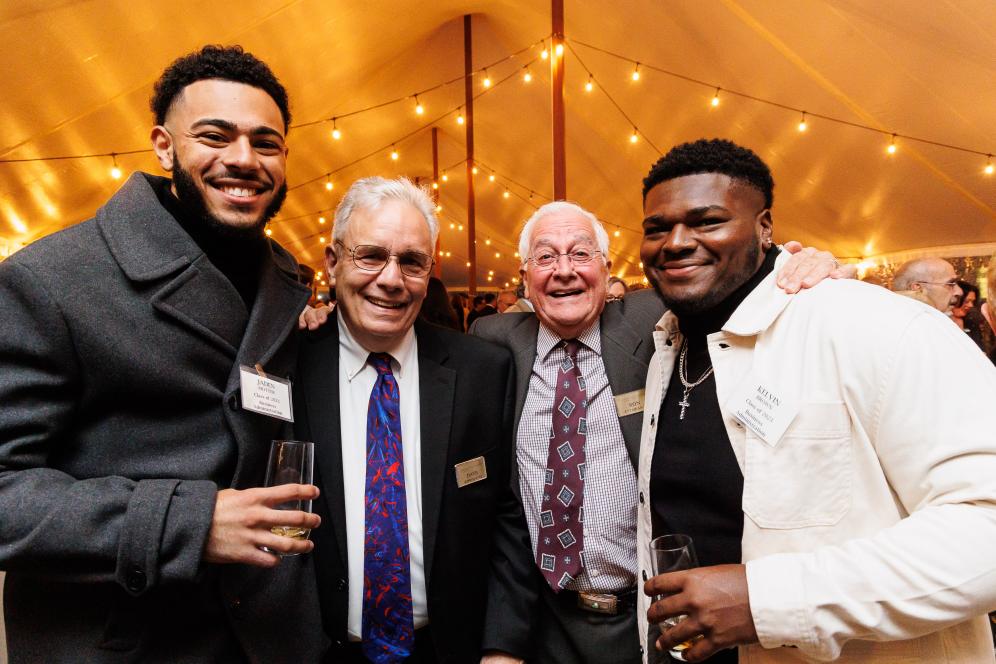 Two young alumni pose for a photo with two older alumni at 1896 dinner. 