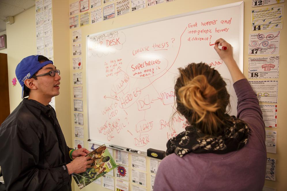 Students are writing on a white board at the writing center. 