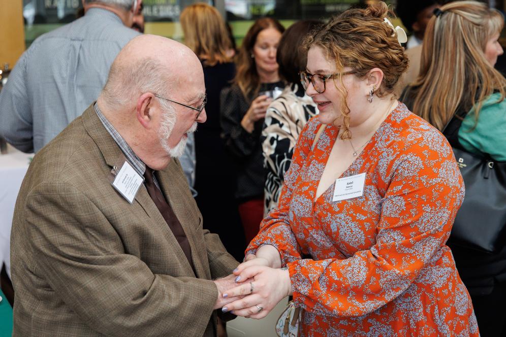 A student is with a scholarship donor, shaking their hand in the life sciences building. 