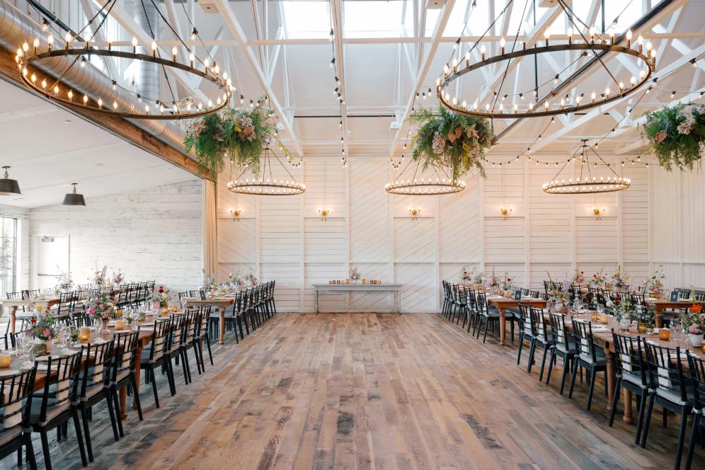 Terrain event venue in the day time with tables, chairs, and chandeliers. 