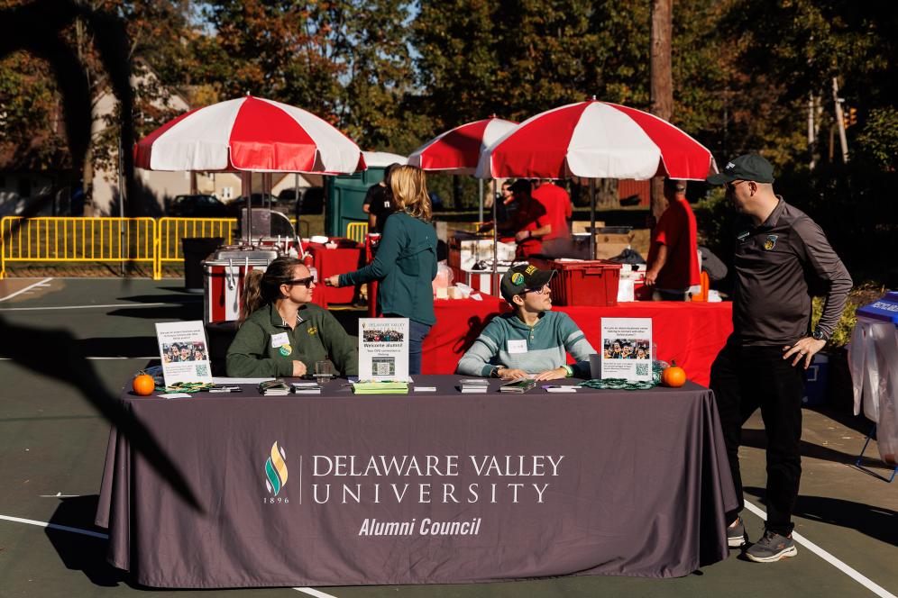 The alumni council table at homecoming with two representatives