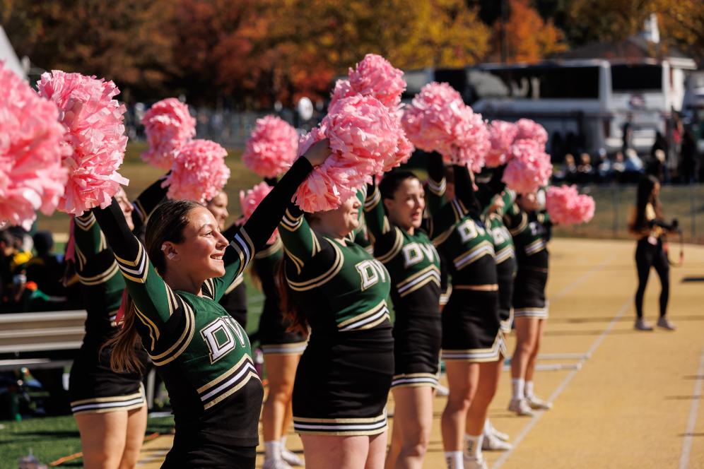 Cheerleaders on the field with pink pompoms