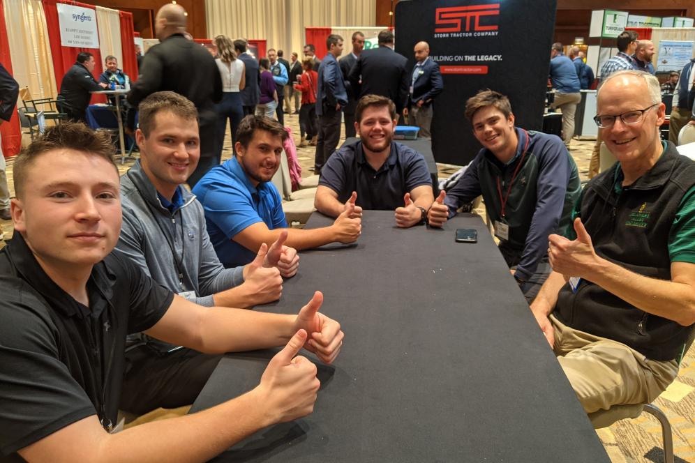 Students are at a conference table with Dr. Linde, and all are smiling at the camera.