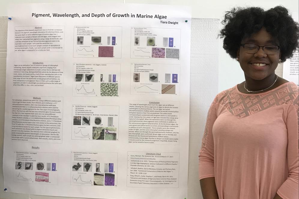 Tiara Dwight, a student, is standing beside her research poster.
