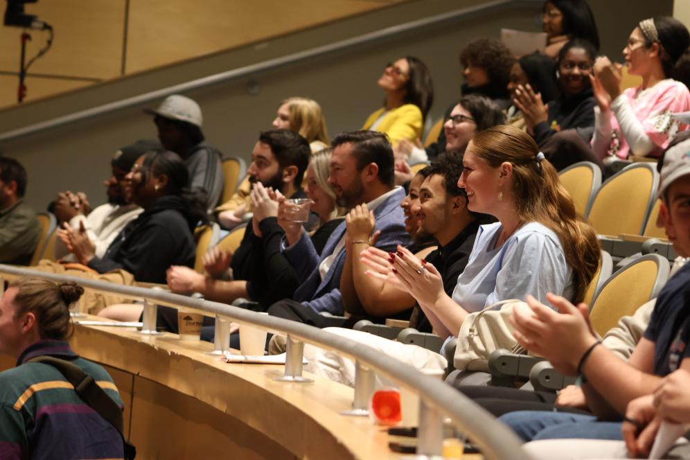 Students are in the crowd clapping for a presenter on stage. 
