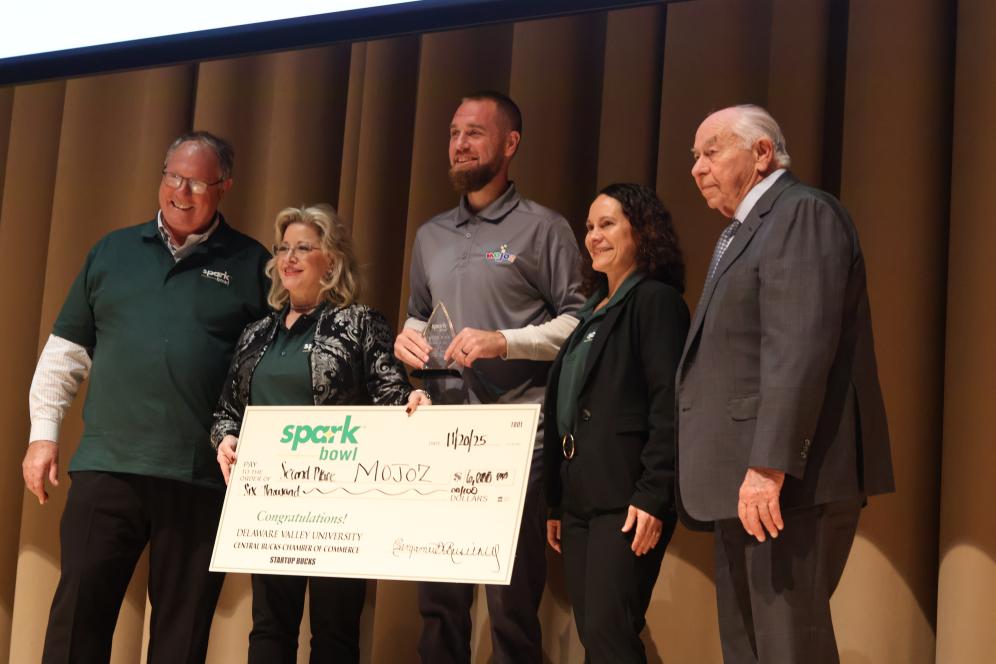 Our second place spark bowl winners MOJOZ are on stage holding a giant check.