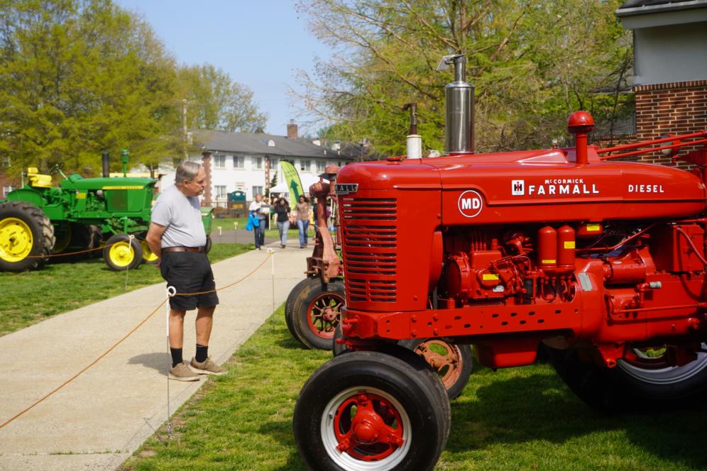 A man is observing an antique red tractor at the tractor show at A-Day. 