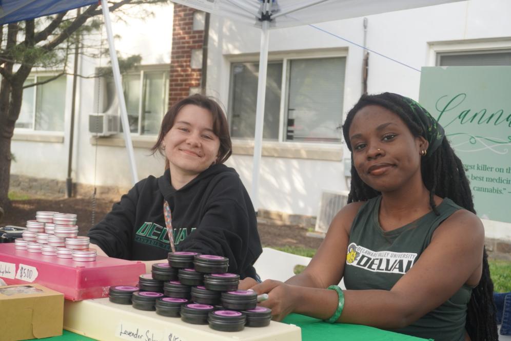 Two students from a club are displaying their club table full of items to purchase.