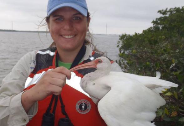 A student working on Sanibel island holding a sea bird
