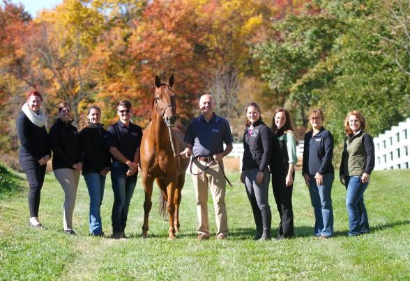 Students and faculty member standing with horse in a field