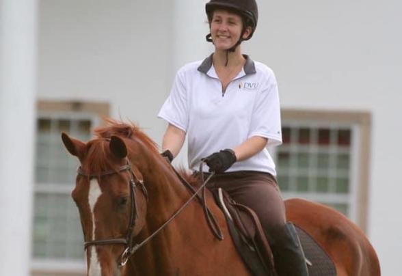 Jillian McNellis riding a horse on campus