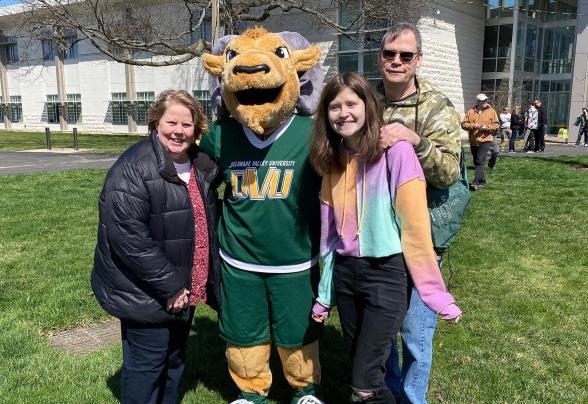 A family poses with Caesar the mascot at green and gold day. 
