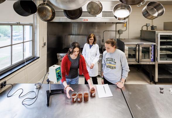 two students and a professor are working in the food science lab