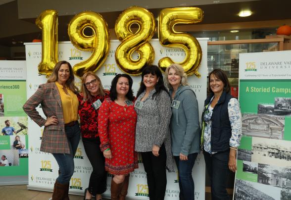A group of women from the class of 1985 pose in front of big balloons which say 1985