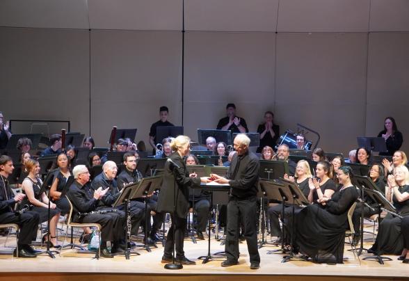 Musicians are dressed in all black and seated on stage at the LSB auditorium. 