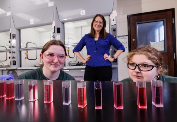 Melissa Langston with students in the lab looking at viles of liquid. 