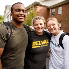 3 students in a group looking happy.