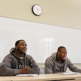 Two male students looking towards the front of the classroom.