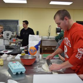 A student rolling out dough in the food lab