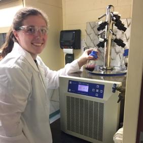 Female student in lab coat with safety glasses in laboratory