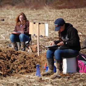 Students seated near soil at soil contest