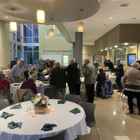 Alumni gathered around tables set up with flowers and silverware.