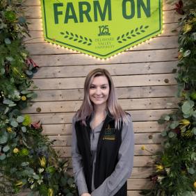 DVU student in front of a 'farm on' sign