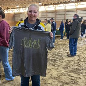 A student is holding up a tshirt that says delval