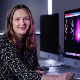 Media and Communications student is sitting in front of a MAC computer with her work.