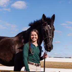 Nina Dellarte '21 standing with a horse.