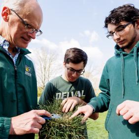 Professor Doug Linde is working with two students on the field. 