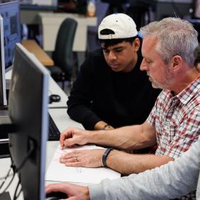 Professor Fleischaker and two students are working on a computer. 