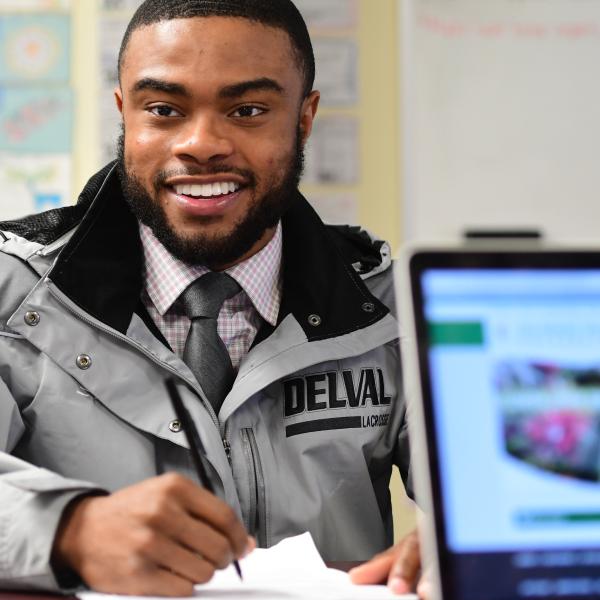 Business attire clad male student holding a pen taking notes