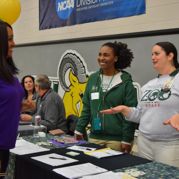 A student talking to representatives from the Philadelphia Zoo at a job fair