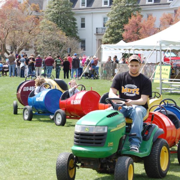 A student driving a lawn mower pulling train cars with passengers