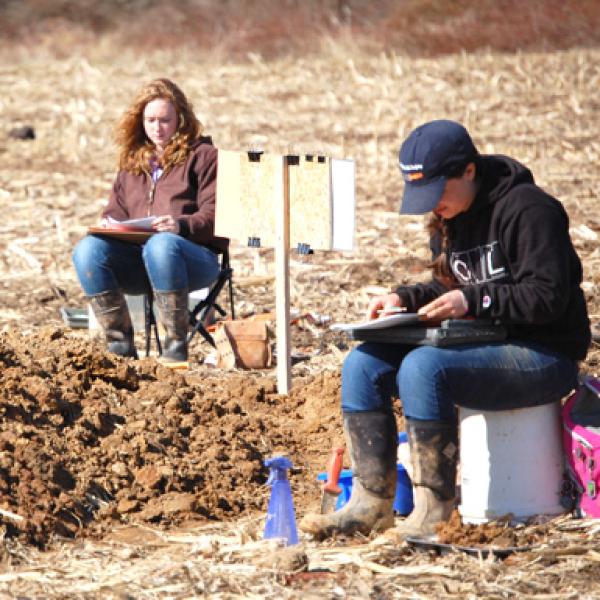 2 students in a filed surrounded by soil