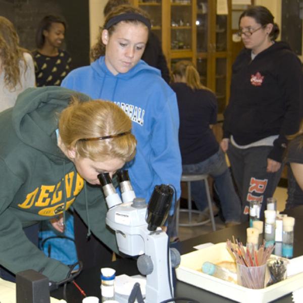 a student looking onto a microscope