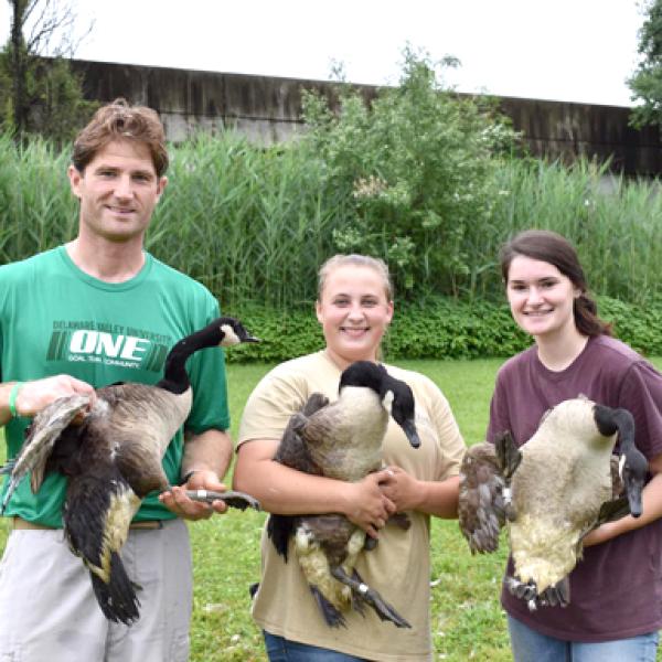 an advisor and students holding Canadian geese