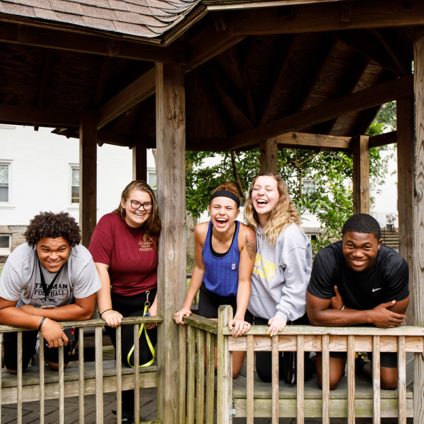 A group of five Delaware Valley University students smile in a gazebo on the University's scenic campus. 