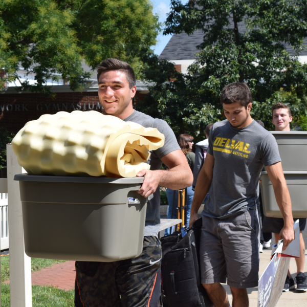 Two students carry boxes of belongings into a residence hall at Delaware Valley University on Move-In Day.